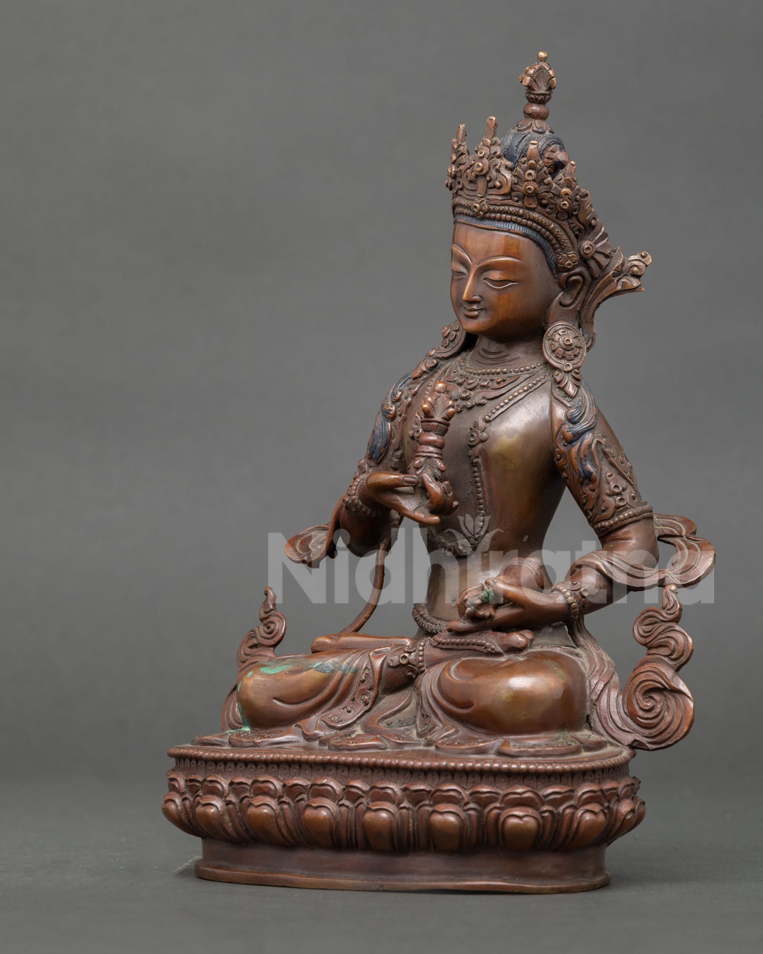 Vajrasattva statue seated in vajraparyanka posture holding vajra and ritual bell.