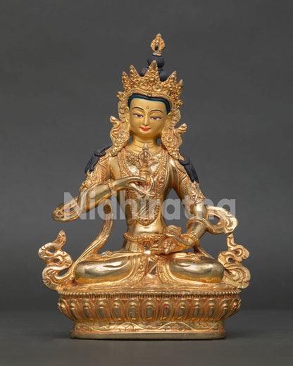 Vajrasattva statue seated on lotus pedestal holding five pronged vajra and bell.