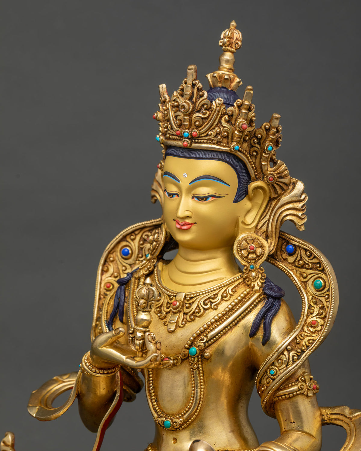 Vajrasattva statue side close up, vajra and bell hand detail, carved robe