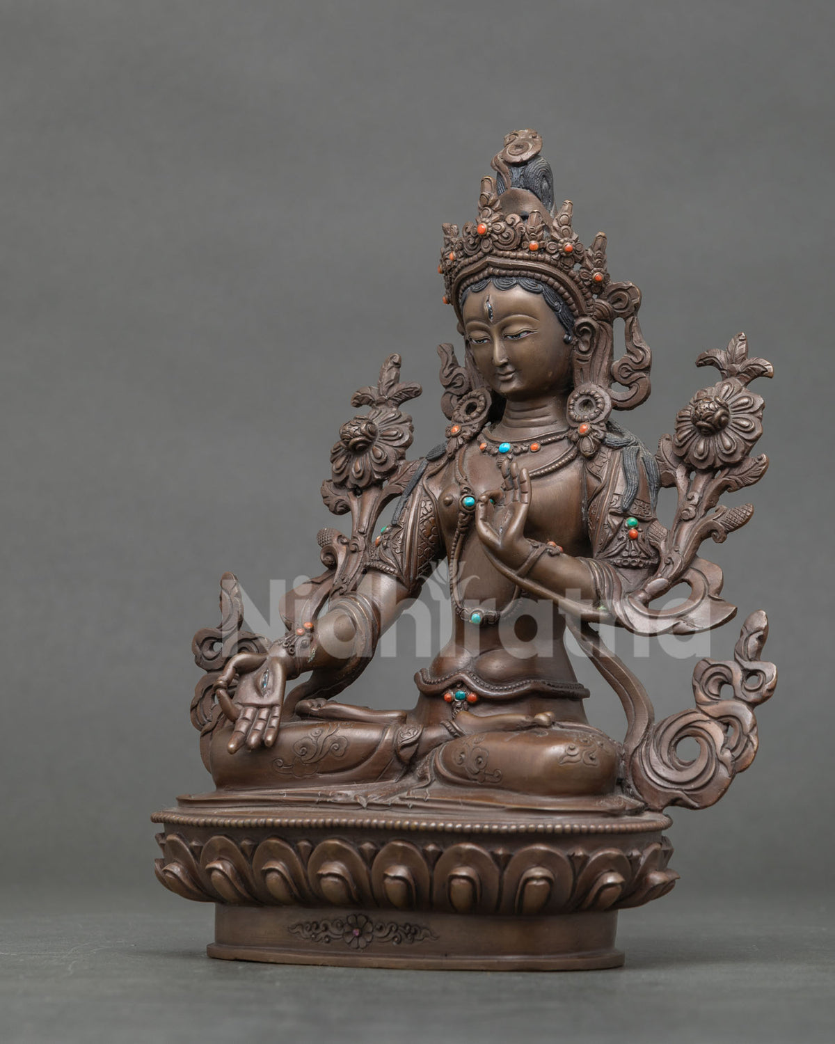 White Tara buddhist statue with layered necklaces and floral garment.