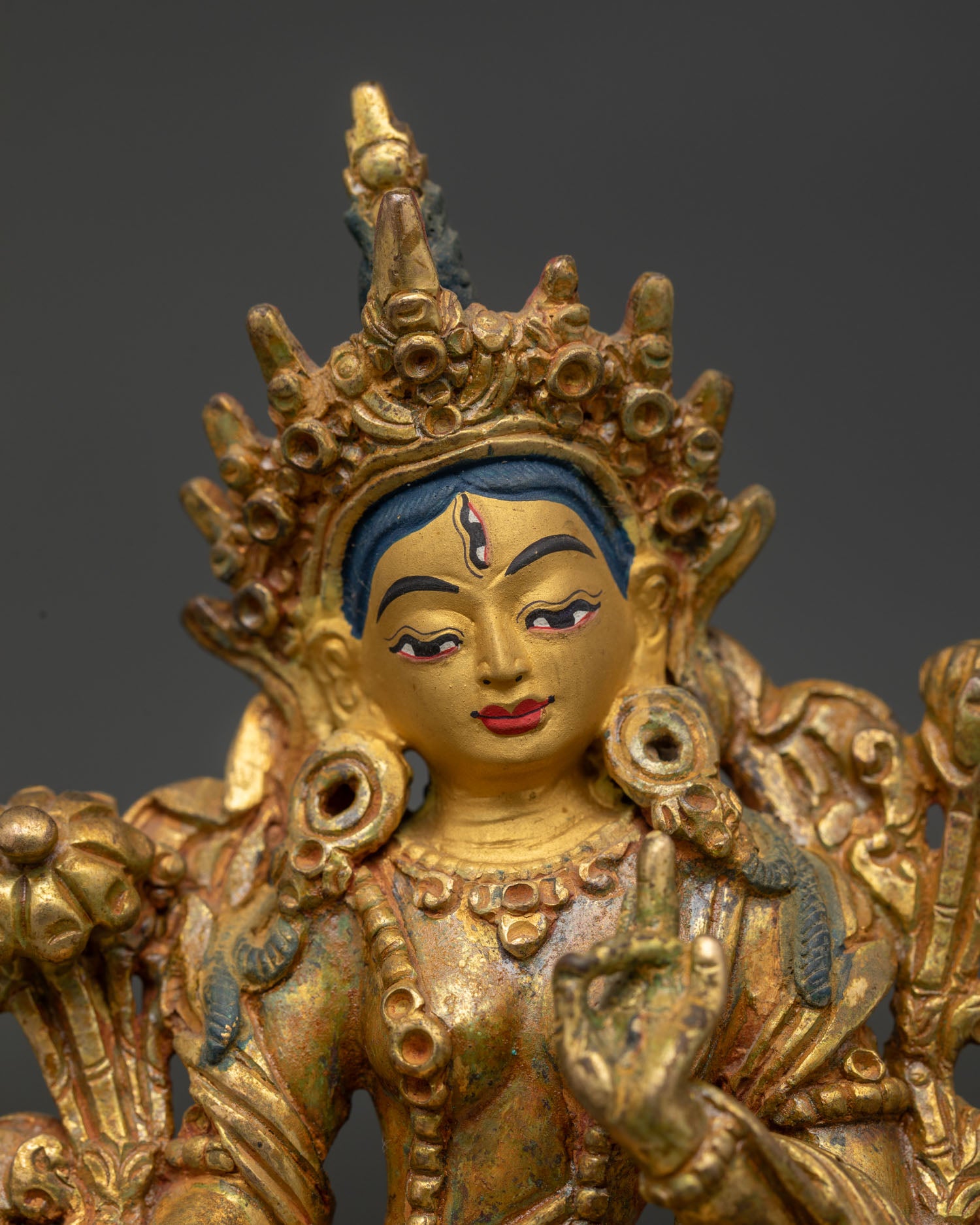 White Tara detailed face view gold painted face jeweled crown and serene expression.