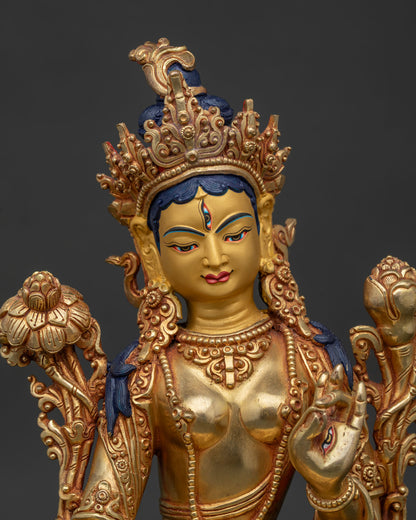 White Tara statue close up showing gold painted face and floral motif robe.