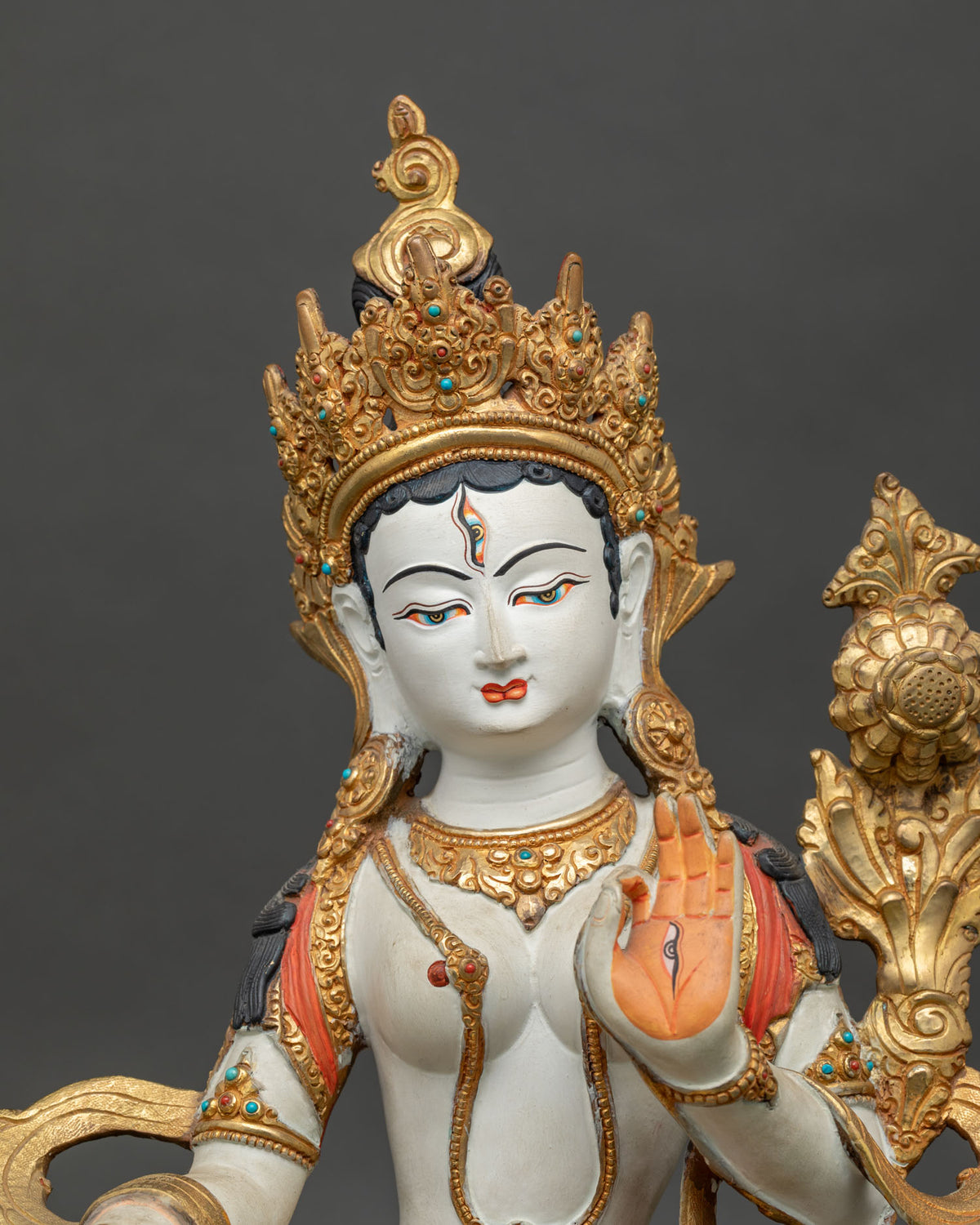 White Tara statue with a five jewel crown layered necklaces and floral carved silk garment.