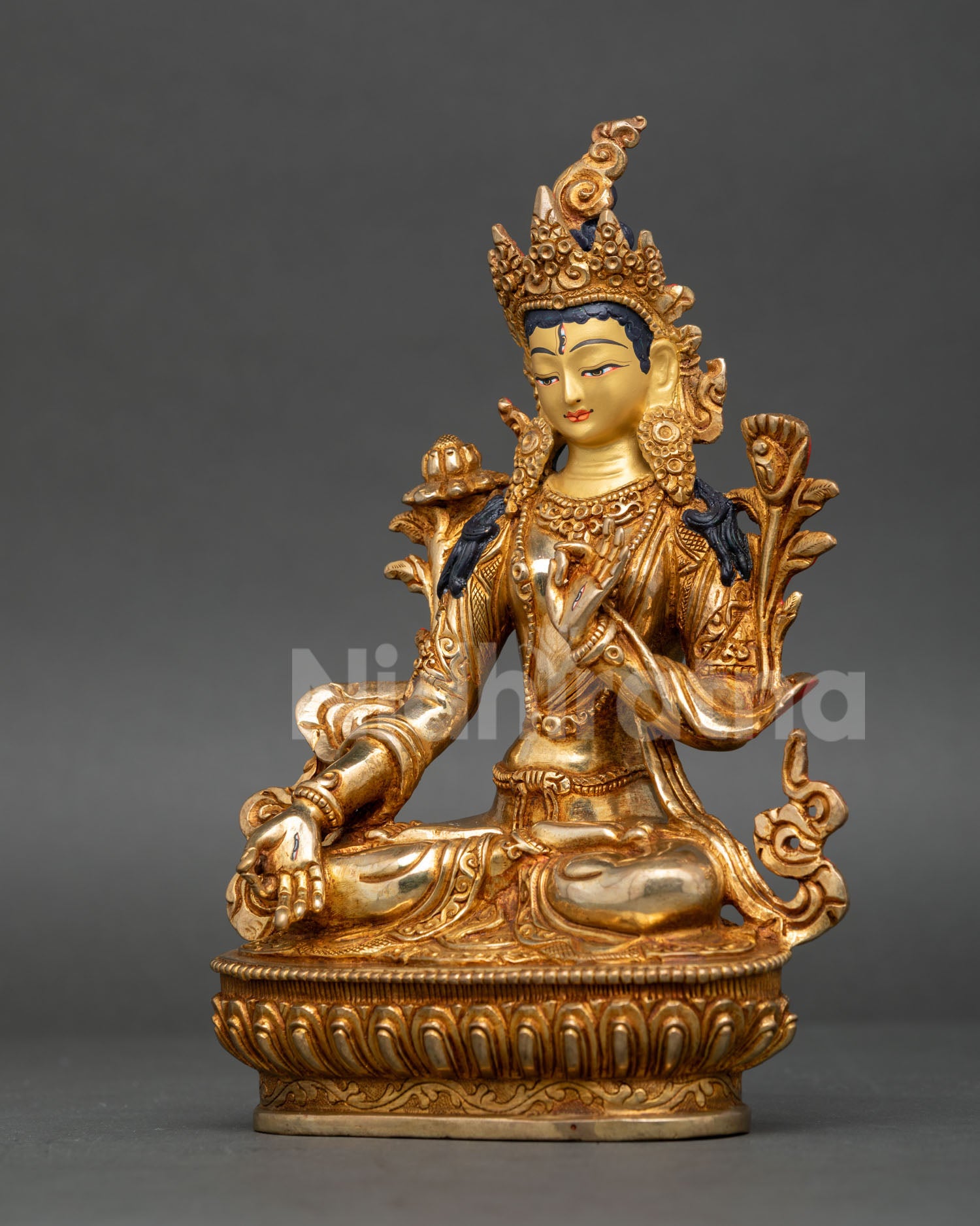 White Tara statue in fire, gilded copper seated in vajra posture on lotus throne.