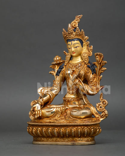 White Tara statue in fire, gilded copper seated in vajra posture on lotus throne.