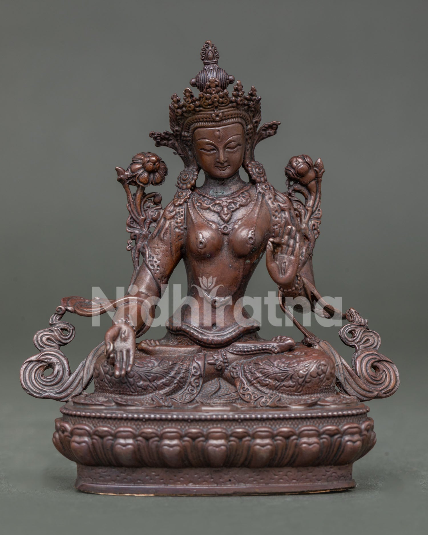 White tara statue seated on lotus throne in vajra posture holding white lotus.