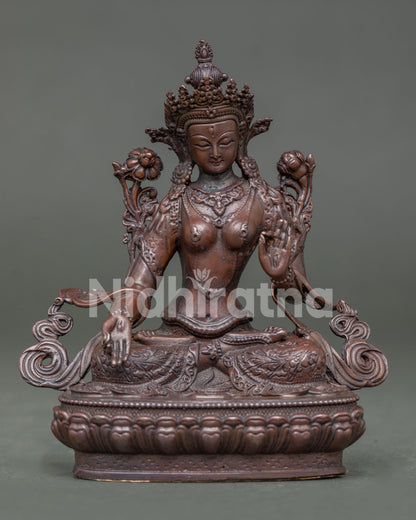 White tara statue seated on lotus throne in vajra posture holding white lotus.