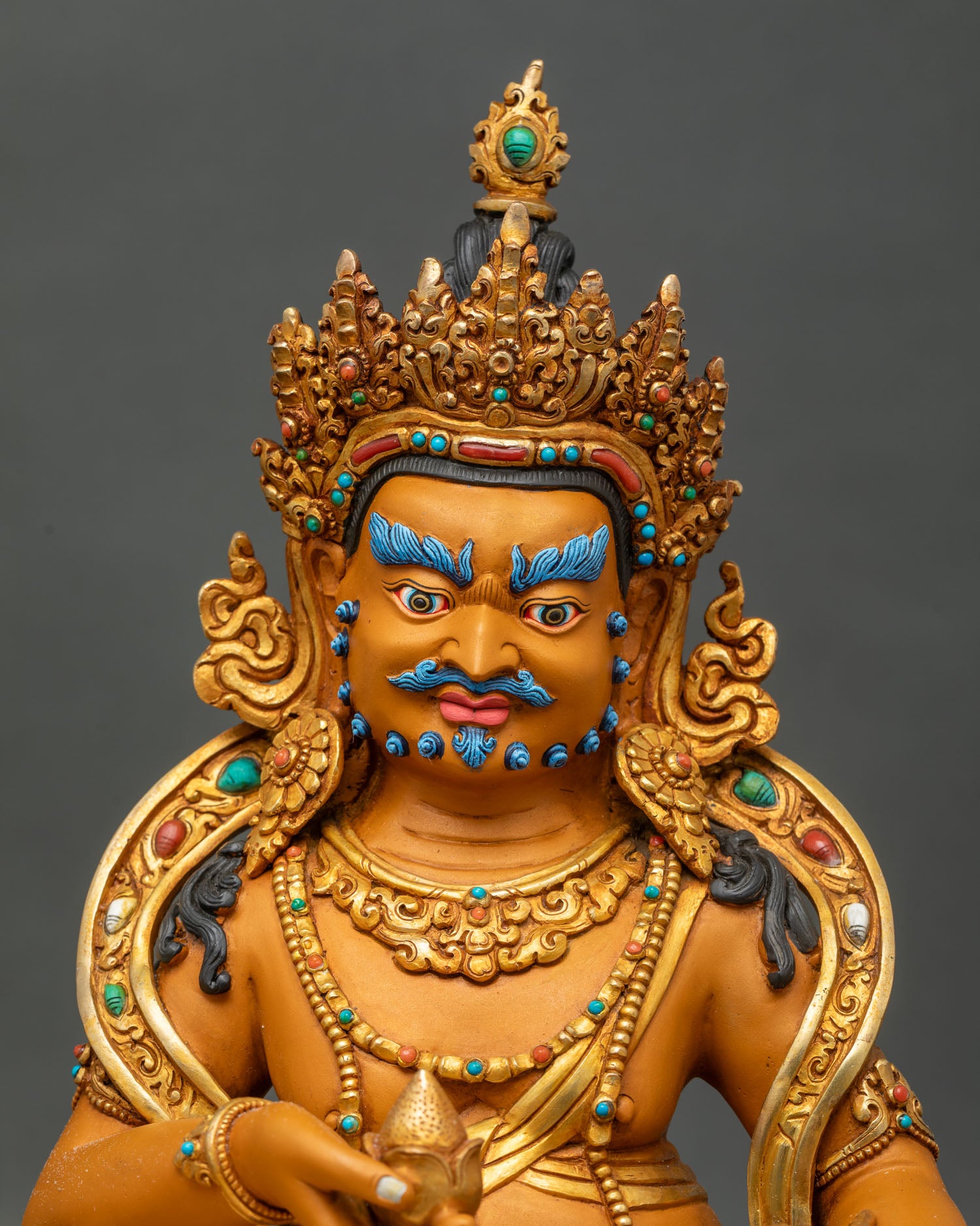 Yellow Dzambhala face close-up blue eyebrows gemstone crown Himalayan Buddhist deity