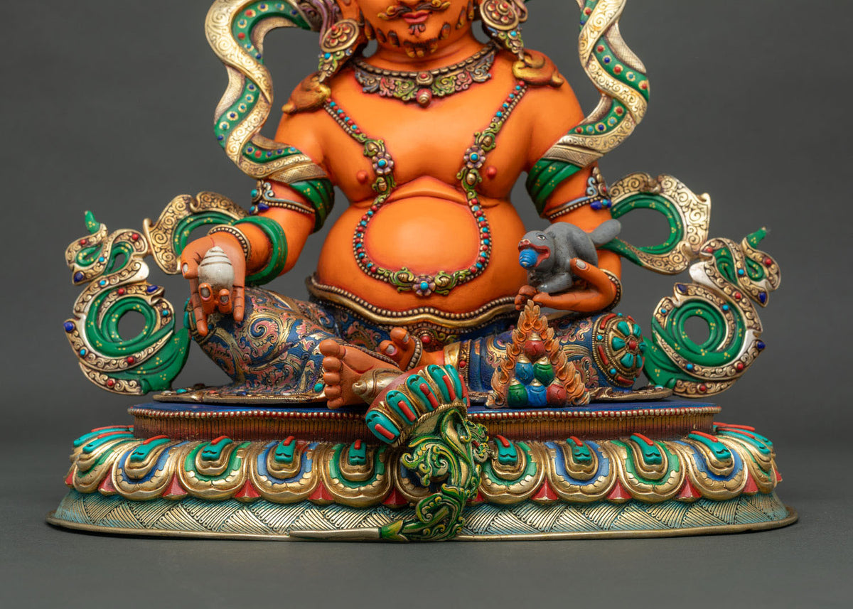 Yellow Dzambhala statue with extended right foot resting on a white conch shell, representing victory over the fear of poverty.